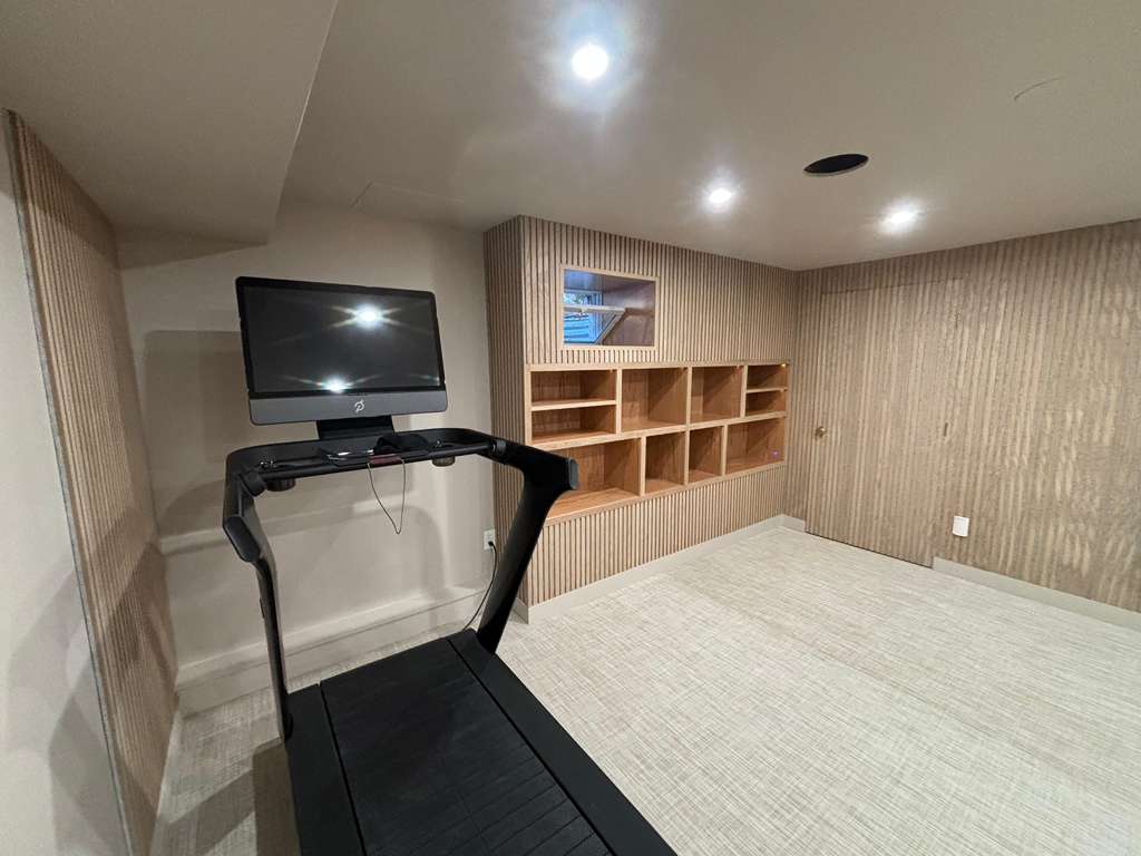 Home gym with white oak fluted panels, designer wallpaper, and handcrafted barn door