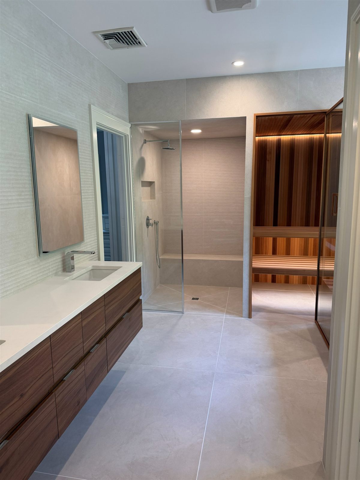 Custom sauna integrated into a master en-suite bathroom with marble and glass